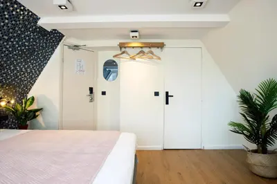 a bedroom with white cabinets and a bed and a plant at Quentin Leidse Square Hotel in Amsterdam