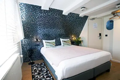 a bedroom with a bed with a blue wall at Quentin Leidse Square Hotel in Amsterdam