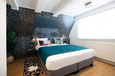 a bedroom with a large bed in a room with black tiles at Quentin Leidse Square Hotel in Amsterdam