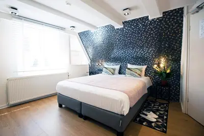 a bedroom with a bed and a wall with blue tiles at Quentin Leidse Square Hotel in Amsterdam