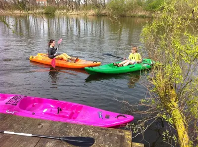 two people are sitting in kayaks on a river at De Groote Wijzend in Lutjebroek