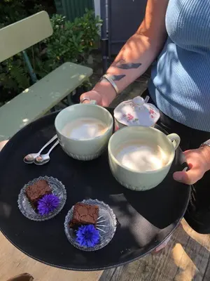 a person holding a tray with two bowls of coffee at De Groote Wijzend in Lutjebroek