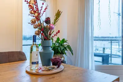 a bottle of wine sitting on a table with a flower arrangement at Watervillashiraz in Aalsmeer