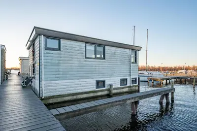 a house on a dock on a body of water at Watervillashiraz in Aalsmeer