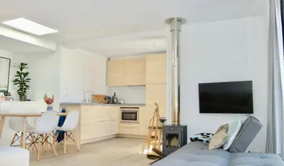 a living room with a blue couch and a kitchen at White Sand Beach in Bergen aan Zee