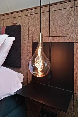 a light bulb hanging from a wall next to a bed at De Nederlanden, Restaurant & Boutique Hotel in Vreeland
