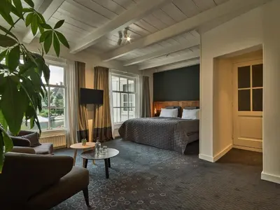a hotel room with a bed and a couch at De Nederlanden, Restaurant & Boutique Hotel in Vreeland