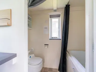 a small bathroom with a toilet and a bath tub at Holiday home in Burgerbrug near the beach in Burgerbrug