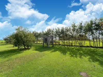 a shed in a field with a fence and trees at Holiday home in Burgerbrug near the beach in Burgerbrug