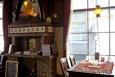 a dining room with a fireplace and a table with chairs at Hotel Internationaal in Amsterdam
