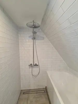 a shower in a white bathroom with a bath tub at Hotel Internationaal in Amsterdam