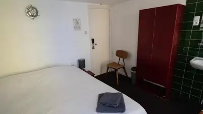 a bedroom with a bed and a sink and a chair at Hotel Internationaal in Amsterdam