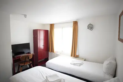 a hotel room with two beds and a desk and a window at Hotel Internationaal in Amsterdam