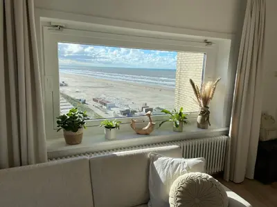 a living room with a window with a view of the beach at Sea La Vie- Appartement aan het strand in Zandvoort aan Zee! in Zandvoort