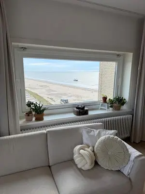 a living room with a couch and a large window at Sea La Vie- Appartement aan het strand in Zandvoort aan Zee! in Zandvoort
