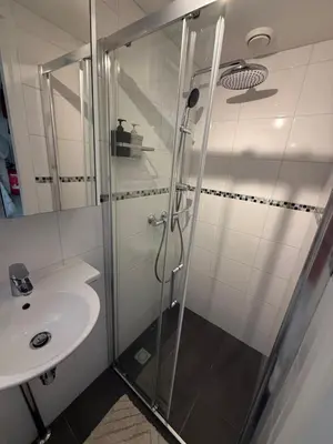 a shower with a glass door next to a sink at Sea La Vie- Appartement aan het strand in Zandvoort aan Zee! in Zandvoort