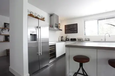 a kitchen with white cabinets and a stainless steel refrigerator at Villa M in Schoorl