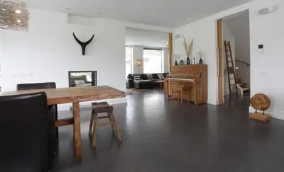 a living room with a wooden table and a piano at Villa M in Schoorl