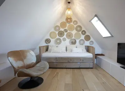 a attic bedroom with a bed and a chair at Villa M in Schoorl