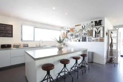 a kitchen with a white counter and stools in it at Villa M in Schoorl
