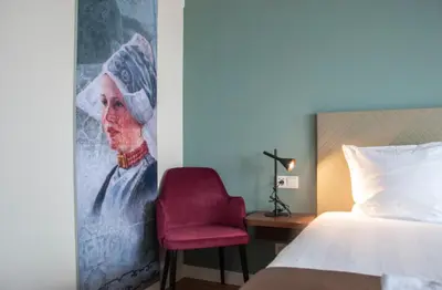 a bedroom with a bed and a red chair at Hotel Spaander BW Signature Collection in Volendam