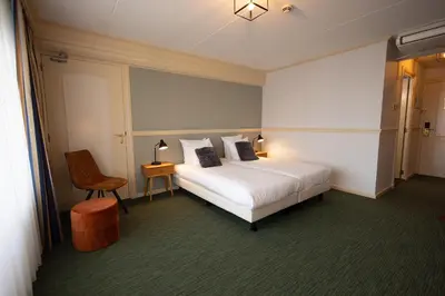 a hotel room with a bed and a chair at Hotel Spaander BW Signature Collection in Volendam