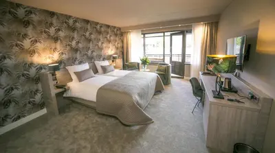 a bedroom with a bed and a desk and a television at Van der Valk Hotel Avifauna in Alphen aan den Rijn