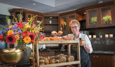 a woman is standing in a kitchen with flowers at Van der Valk Hotel Avifauna in Alphen aan den Rijn