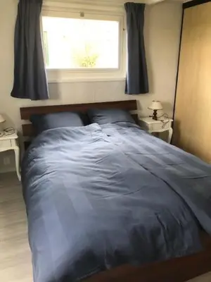 a bedroom with a blue bed with a window at gouwzicht in Amsterdam