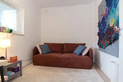 a living room with a brown couch and a painting at B&B Amsterdam West in Amsterdam