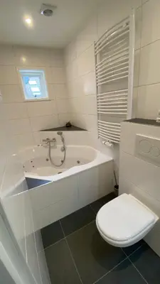 a bathroom with a toilet and a bath tub at Hotel 1900 in Bergen