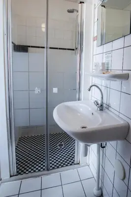a white bathroom with a sink and a shower at Hotel 1900 in Bergen