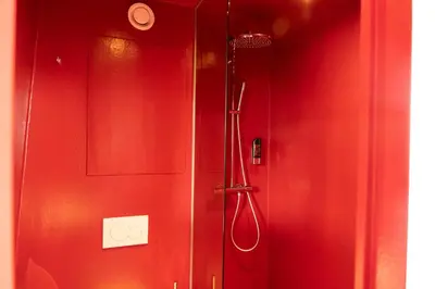 a shower in a bathroom with a red wall at Botel in Amsterdam