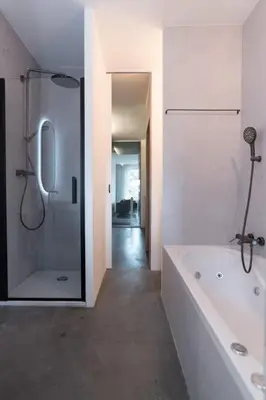 a white bathroom with a tub and a shower at City centre Loft on the historic Canal in Utrecht
