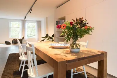 a dining room table with a vase of flowers on it at City centre Loft on the historic Canal in Utrecht