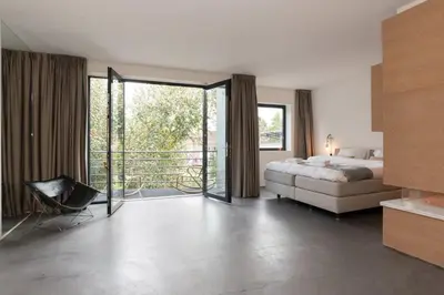 a bedroom with a bed and a sliding glass door at City centre Loft on the historic Canal in Utrecht