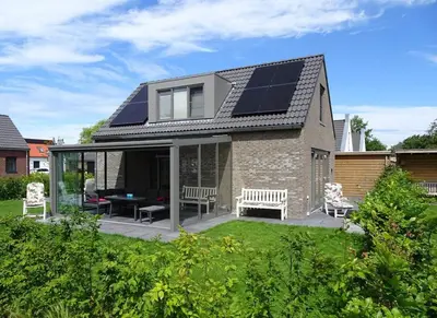 a house with solar panels on the roof at Bungalow 71 op Recreatiepark De Wielen in Sint Maarten