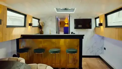 a bar with green stools in a room at Unieke beleving op het water, de Prinsenboot. in Spaarndam