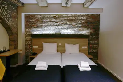 a bedroom with a large bed with a brick wall at City Hotel Amsterdam in Amsterdam
