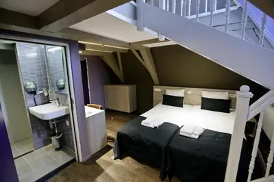 a bedroom with a bed and a sink and a staircase at City Hotel Amsterdam in Amsterdam