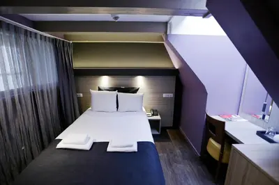 a bedroom with a bed with white sheets and pillows at City Hotel Amsterdam in Amsterdam