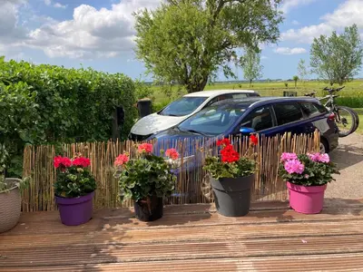 a car parked next to a wooden deck with potted flowers at Het oude strandhuis in Uitgeest