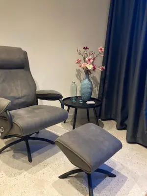 a room with two chairs and a table with a vase of flowers at Het oude strandhuis in Uitgeest