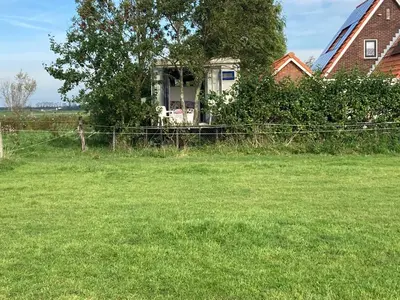 a house in a field with a fence at Het oude strandhuis in Uitgeest