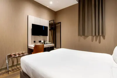 a bedroom with a bed and a desk and a television at Dream Hotel Amsterdam in Amsterdam