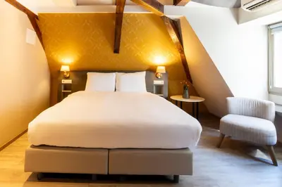 a bedroom with a large bed and a chair at Dream Hotel Amsterdam in Amsterdam