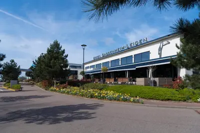 a large building with flowers in front of it at Van der Valk Hotel Sassenheim - Leiden in Sassenheim