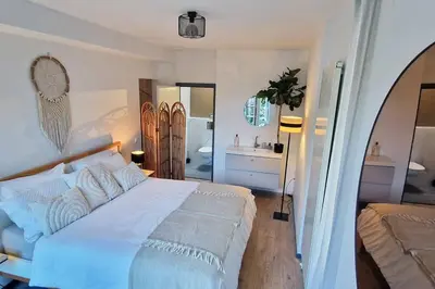 a bedroom with a large white bed and a bathroom at The West Wing Bloemendaal in Bloemendaal