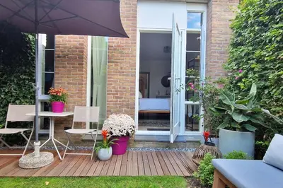 a patio with a table and an umbrella at The West Wing Bloemendaal in Bloemendaal