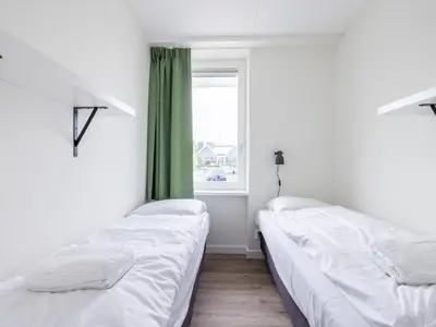 two beds in a room with a window at Lakehouse I in Uitgeest
